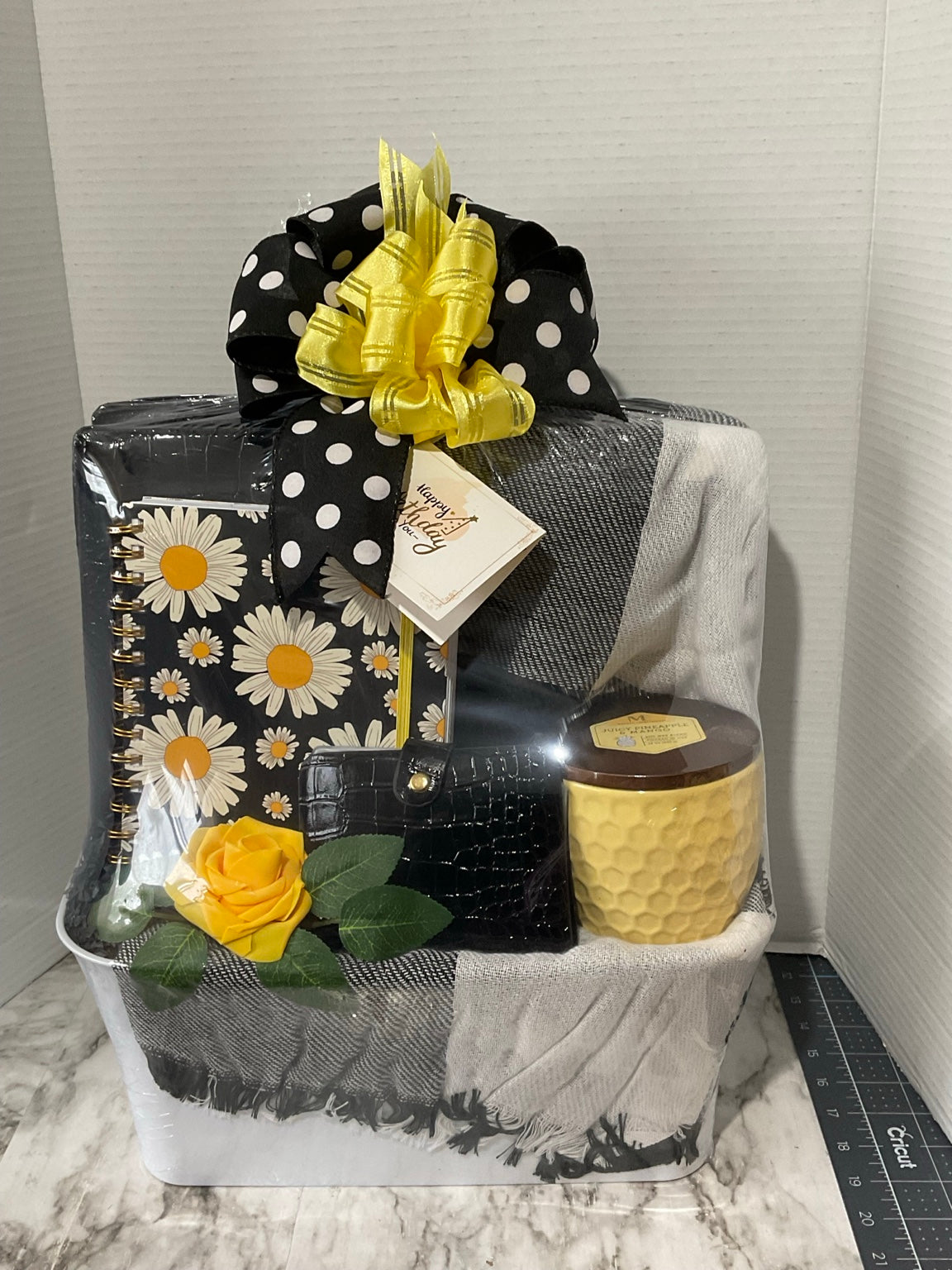 Black, white, and yellow boutique keepsake gift arrangement with journal, handbag, candle, scarf, and flowers