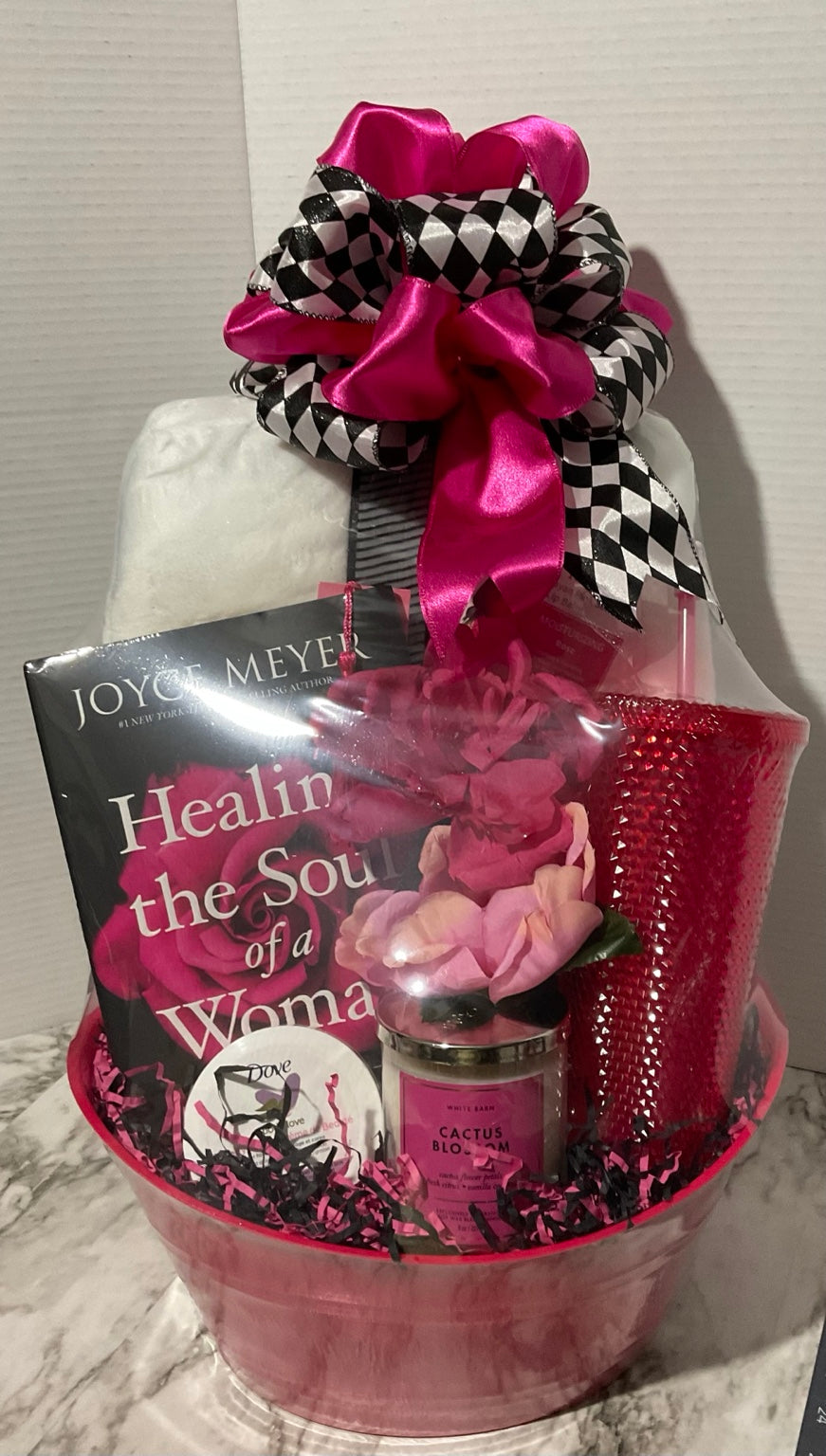 Pink faith and wellness gift basket with devotional book, blanket, candle, tumbler, self-care items, flowers, and boutique bow